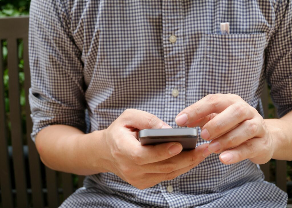 Close-up of a man using a smartphone, focusing on hands and modern technology.